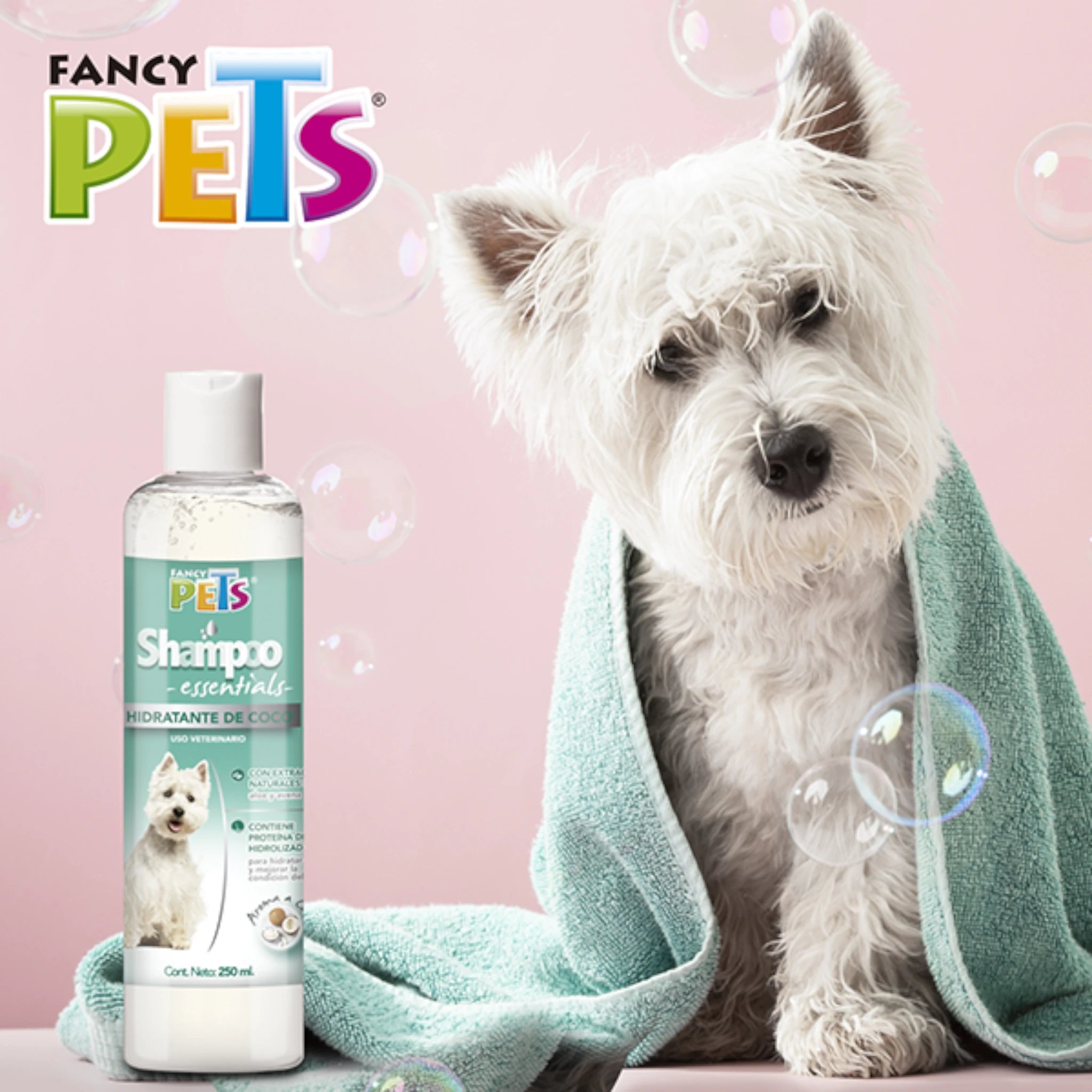 Shampoo hidratante de coco Perro blanco recién bañado envuelto en toalla junto a la botella de Shampoo Essentials Hidratante de Coco Fancy Pets, ideal para hidratar la piel y dar brillo al pelaje.