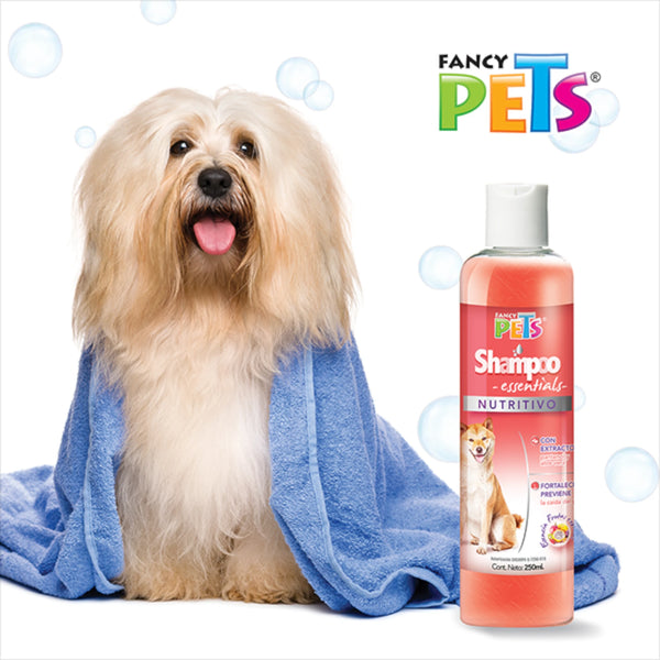 Perro con toalla azul después del baño junto a botella de shampoo nutritivo Fancy Pets, ideal para prevenir la caída del pelo y nutrir su manto