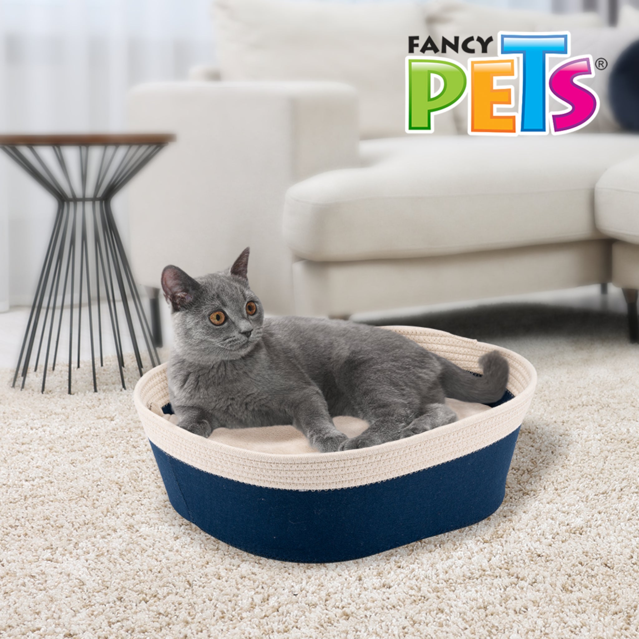 Gato de pelaje gris descansando estirado dentro de la cama canasta azul navy con diseño envolvente.