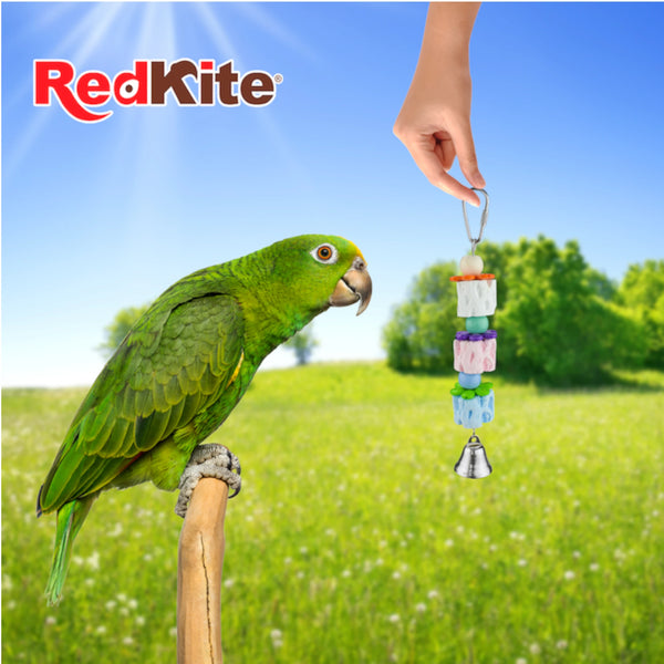 Loro verde observando juguete colgante de calcio RedKite diseñado para entretenimiento y desgaste natural del pico.